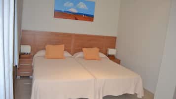 A double bed with two pillows, a nightstand with a lamp, and a painting on the wall.