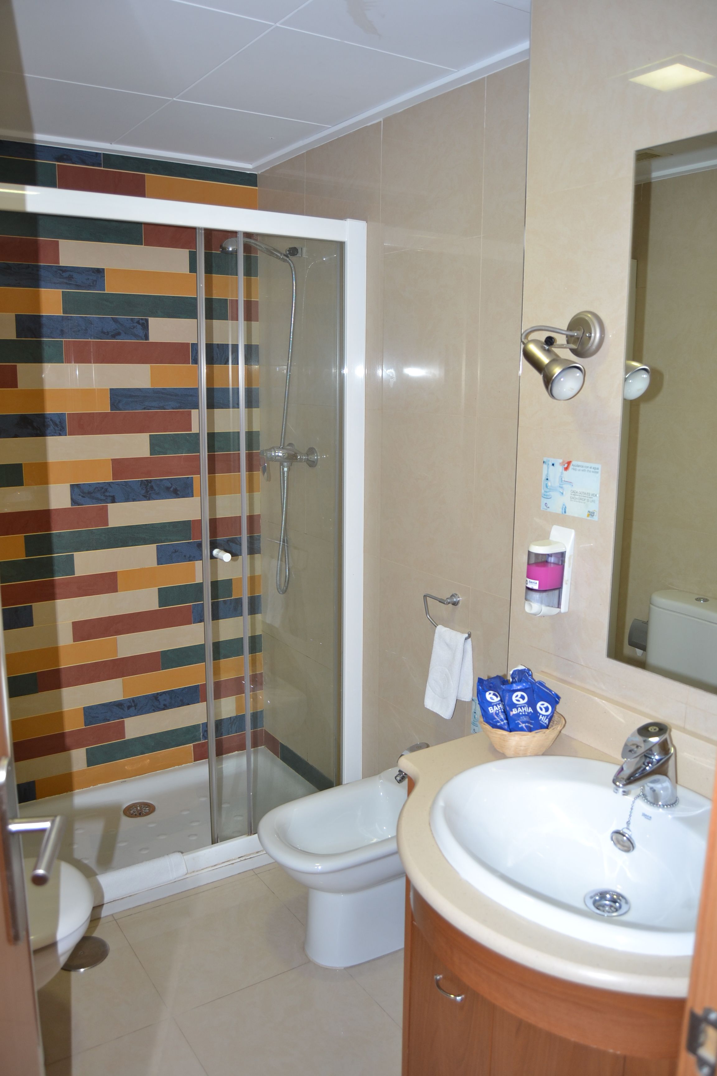Baño con ducha, inodoro, lavabo y espejo.