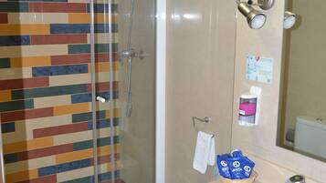 Baño con ducha, inodoro, lavabo y espejo.