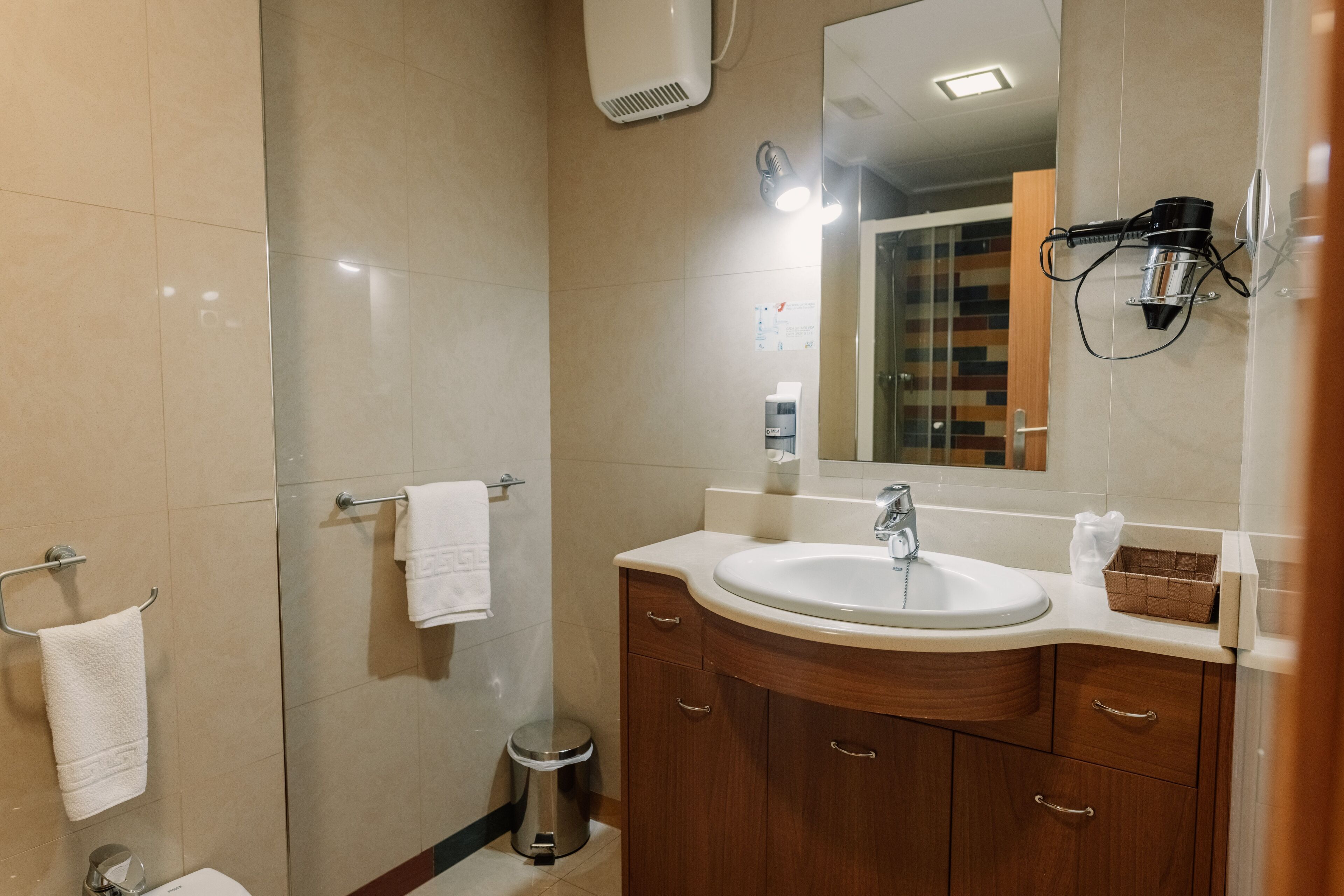 A modern bathroom with a large sink, wooden vanity, and a mirror.