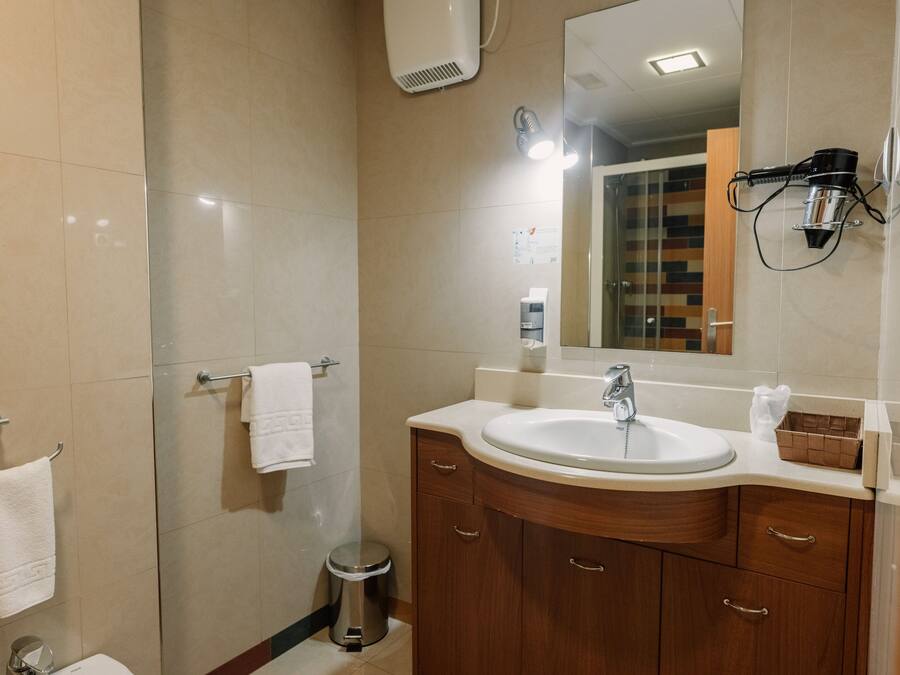 A modern bathroom with a large sink, wooden vanity, and a mirror.