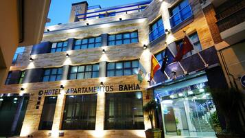 Hotel Apartamentos Bahia features a modern architectural design with large windows and a welcoming entrance.