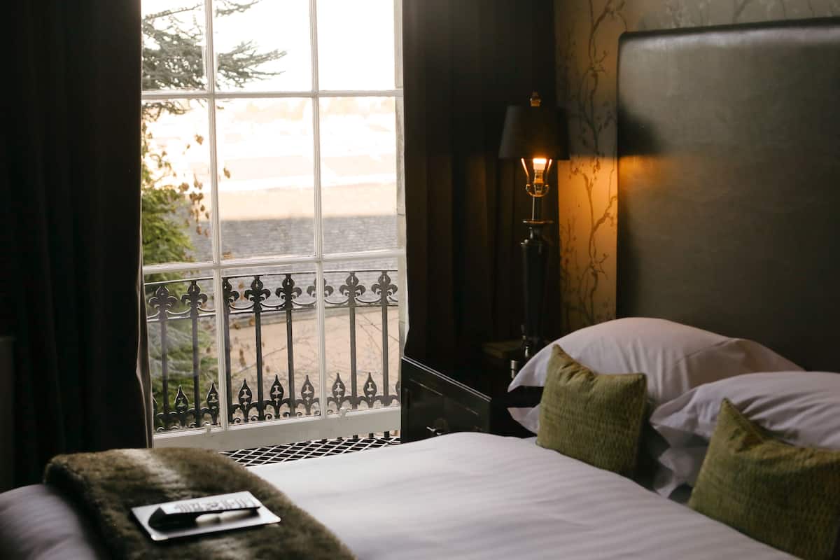 Une chambre d’hôtel avec un lit, une fenêtre donnant sur un paysage agréable, une lampe et une table de chevet.