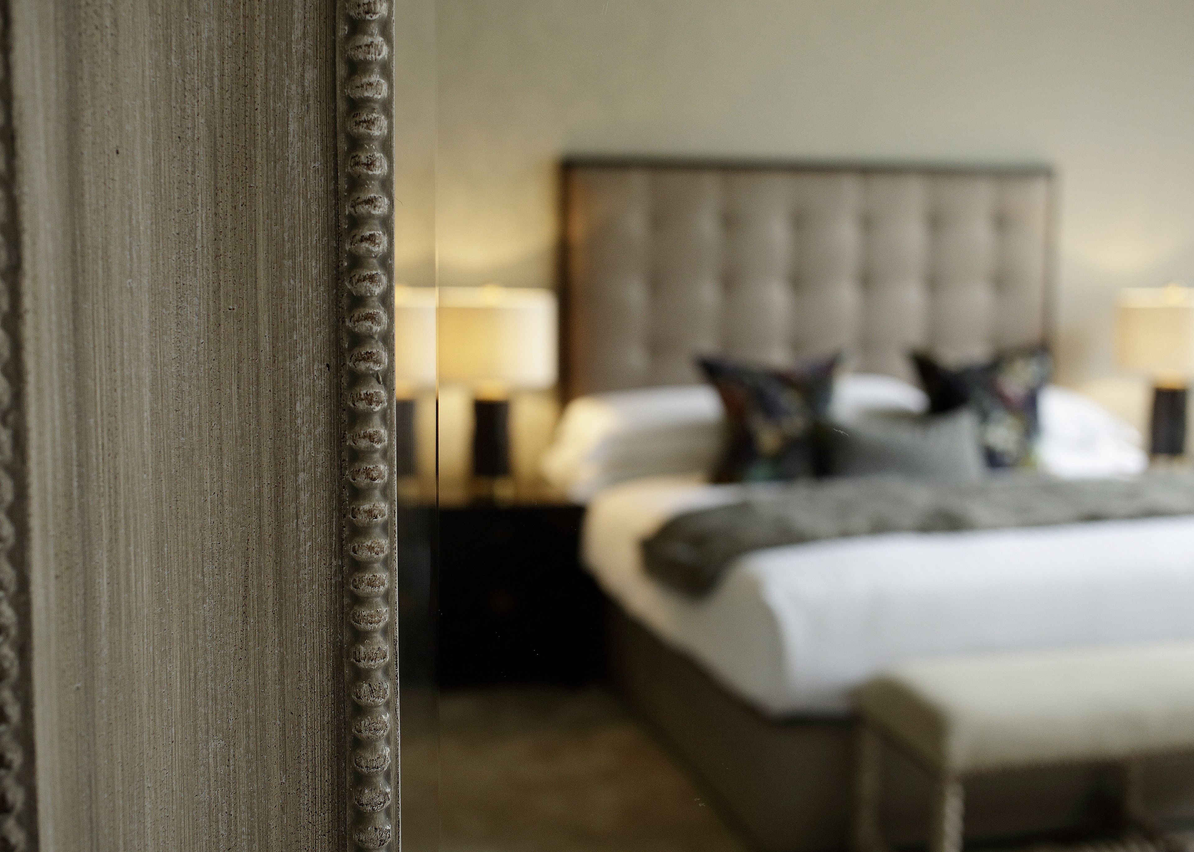 A bedroom with a large bed, bedside tables, and a mirror.