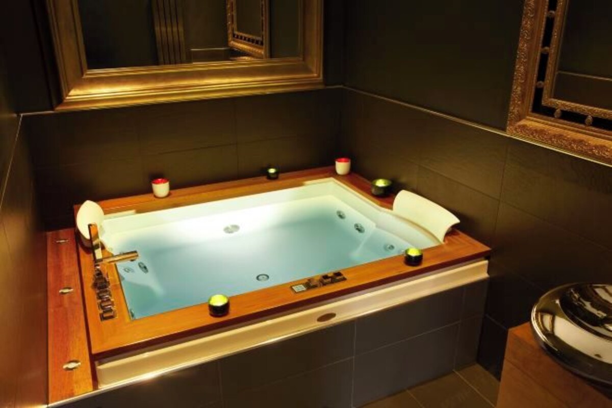 A rectangular hot tub with a wooden frame, a control panel, and a white towel on the edge.