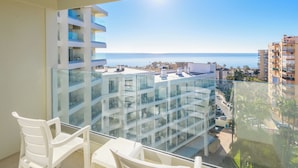 A balcony with a clear view of the sea and surrounding buildings.