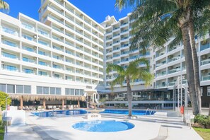 A hotel with multiple floors, a swimming pool, and palm trees. - Hotel Parasol by Dorobe (Torremolinos)