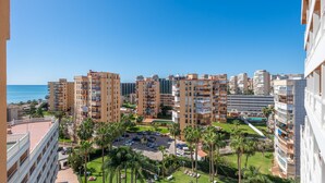 A high-rise residential building complex with multiple balconies, a parking area, and a view of the sea. - Hotel Parasol by Dorobe (Torremolinos)