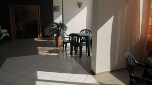A sunlit dining area with a tiled floor, a table, and chairs.