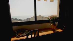 A window with a view of buildings and a vase with flowers on a table.