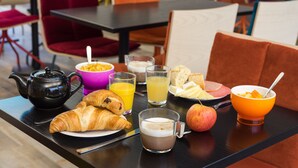 Un desayuno con cruasanes, jugo de naranja, café y fruta sobre una mesa.