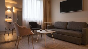 Una sala de estar moderna con un sofá, dos sillones, una mesa de centro y un televisor de pantalla plana montado en la pared.