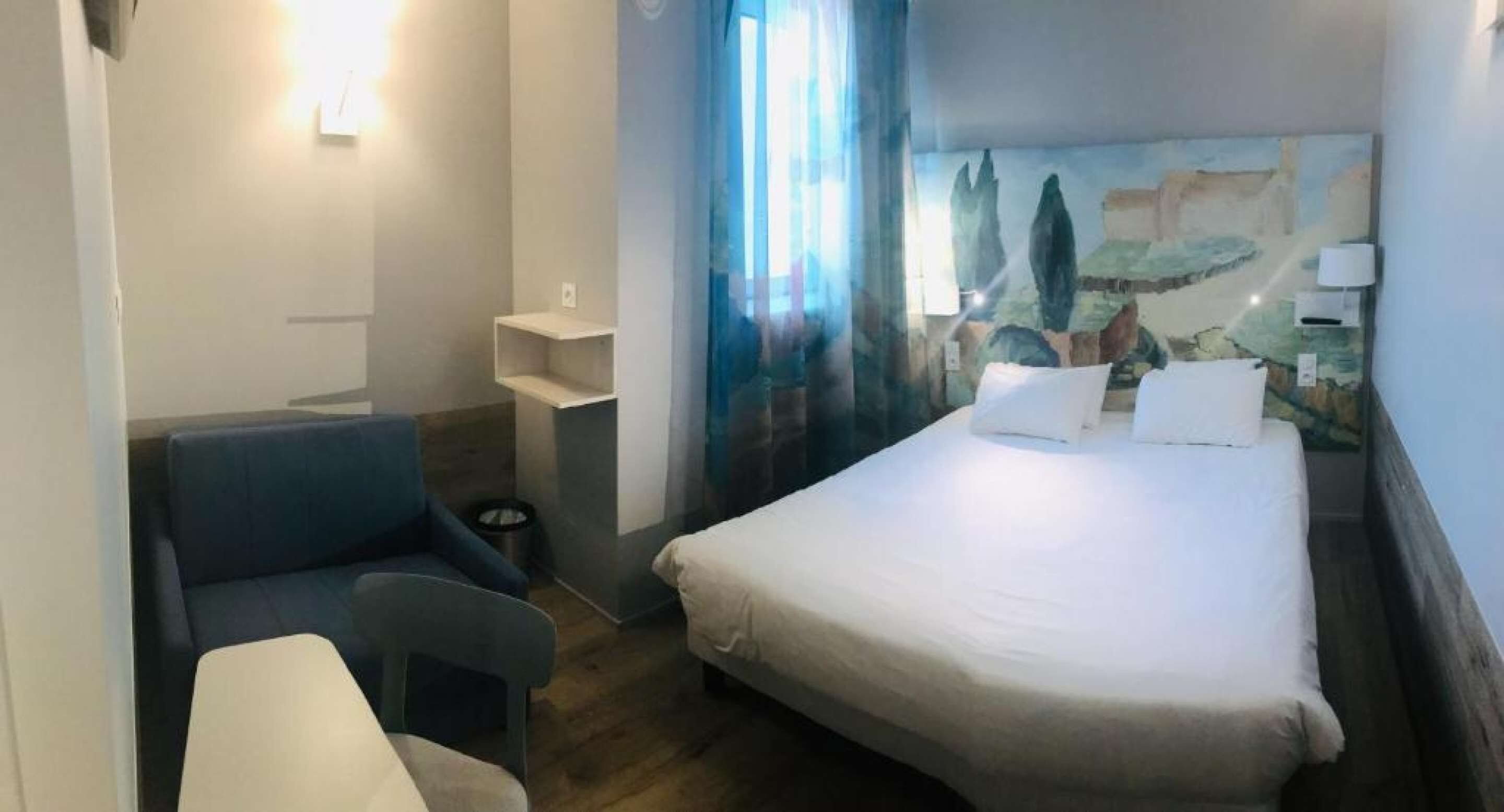 Habitación de hotel con cama, escritorio, silla y una mesita.