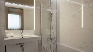 A modern bathroom with a glass-enclosed shower, a sink with a mirror above it, and marble walls.