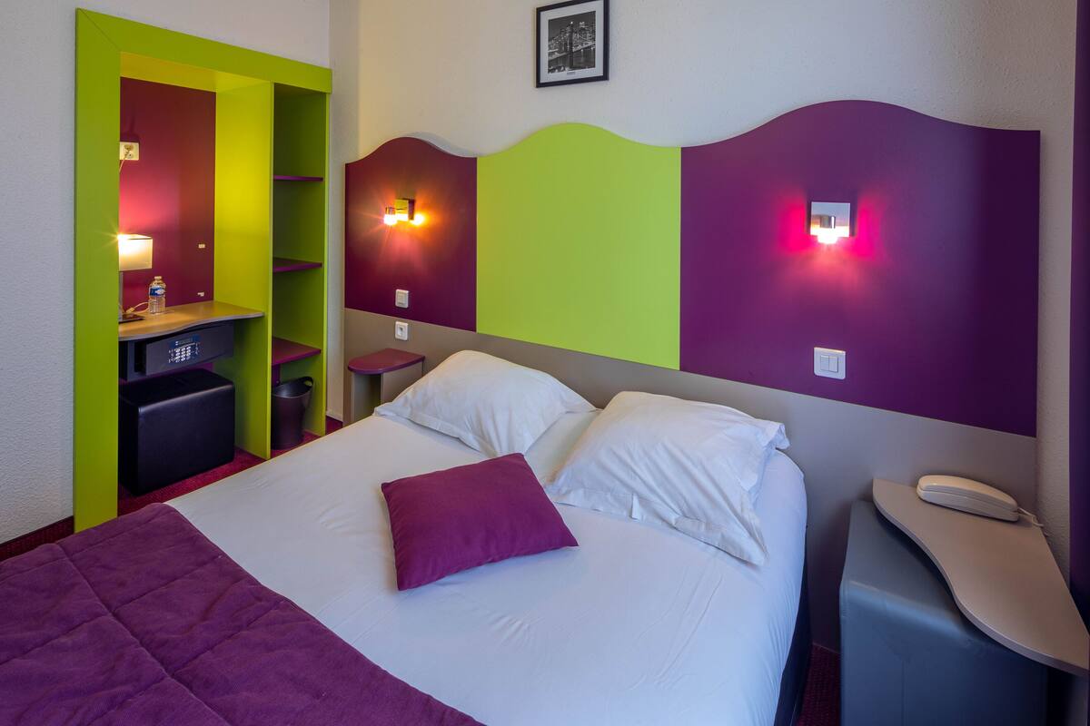 A hotel room with a bed, a desk, and a chair.