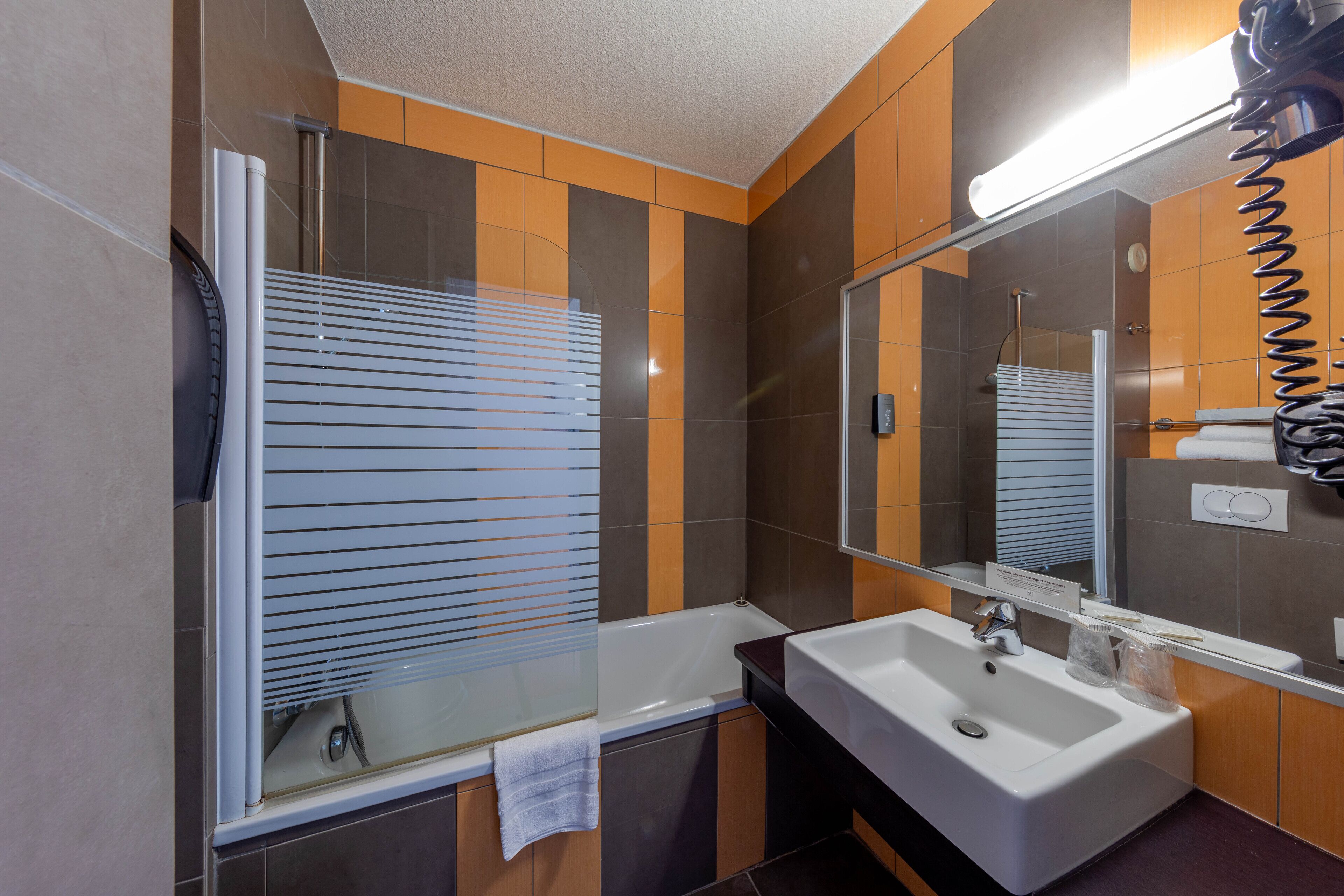 Un baño moderno con bañera, lavamanos y un espejo grande.