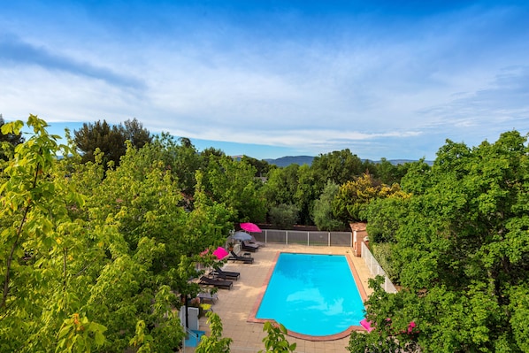 Una piscina al aire libre de temporada, sombrillas
