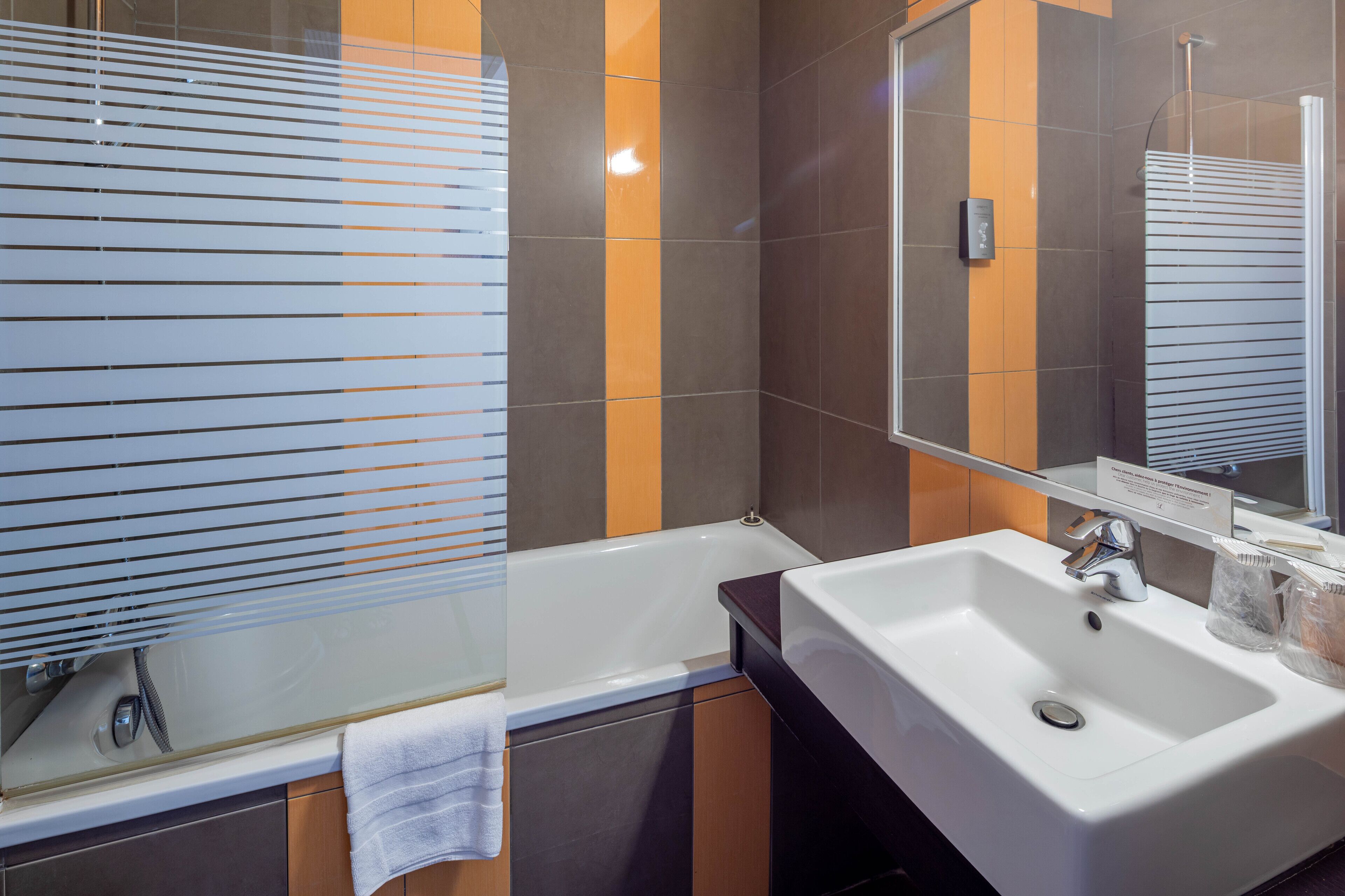 A modern bathroom with a bathtub, a sink, and a mirror.