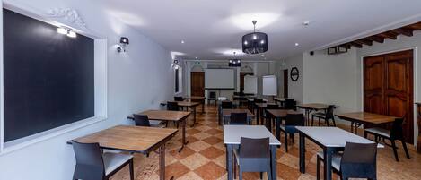 Un aula con una pizarra grande, varias mesas y sillas dispuestas para actividades grupales.