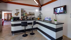 Zona de bar con mostrador, taburetes y televisor montado en la pared.