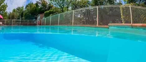 Una piscina al aire libre de temporada, sombrillas, tumbonas