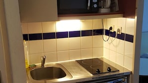 A compact kitchen with a sink, a microwave, a coffee maker, and a compact refrigerator.