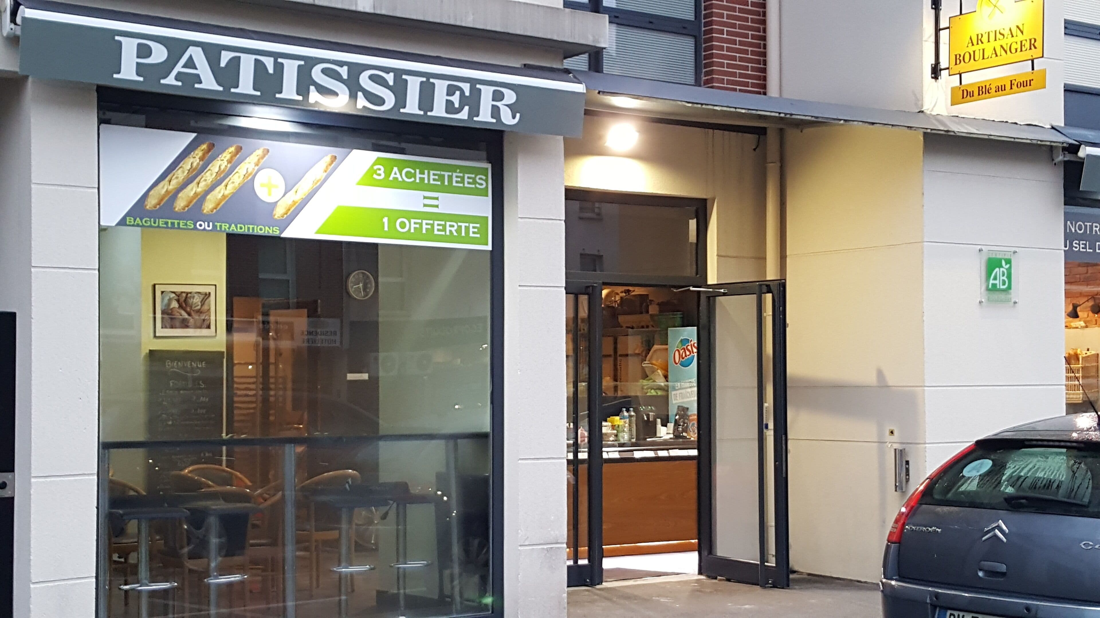 A storefront with a sign reading "PATISSIER" and a menu board advertising "3 ACHETTES" and "1 OFFERTE".