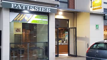 A storefront with a sign reading "PATISSIER" and a menu board advertising "3 ACHETTES" and "1 OFFERTE".