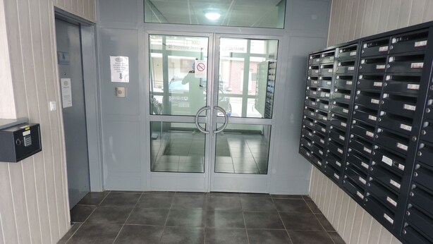 A lobby with a double door, a security keypad, and a wall of mailboxes.