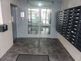 Um hall de entrada com uma porta dupla, um teclado de segurança e um painel de caixas de correio.