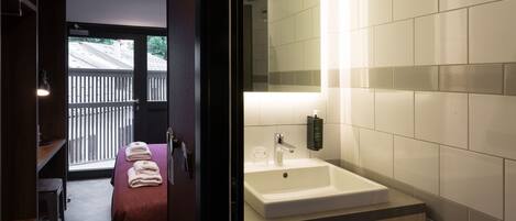 Un baño moderno con un espejo grande, un lavamanos y un banco con toallas.