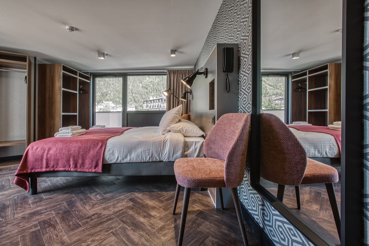 Ett modernt hotellrum med en stor säng, två stolar, ett skrivbord och utsikt över omgivningarna.