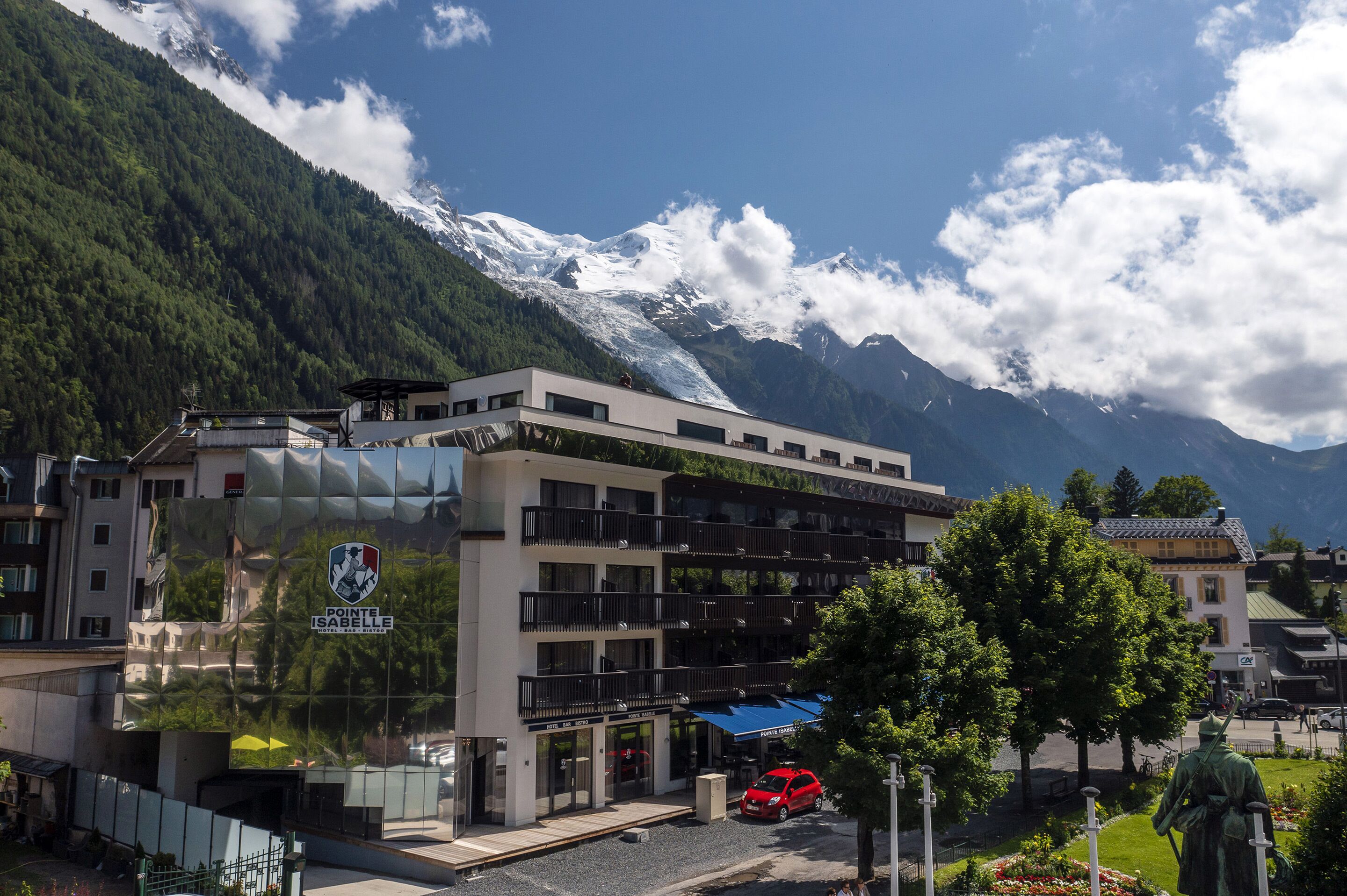 A hotel with a modern design, featuring balconies and a view of snow-capped mountains.
