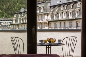 A balcony with a table set for breakfast, including a bowl of fruit and cups. - Pointe Isabelle (Chamonix-Mont-Blanc)