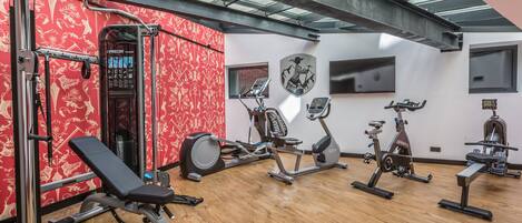 Un gimnasio con diversos equipos de ejercicio, como una banca, elíptica y bicicletas estáticas.