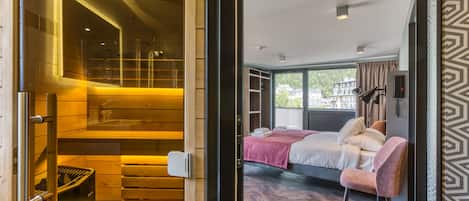 A modern hotel room with a wooden staircase, a bed with a pink blanket, and a view of the city through large windows.