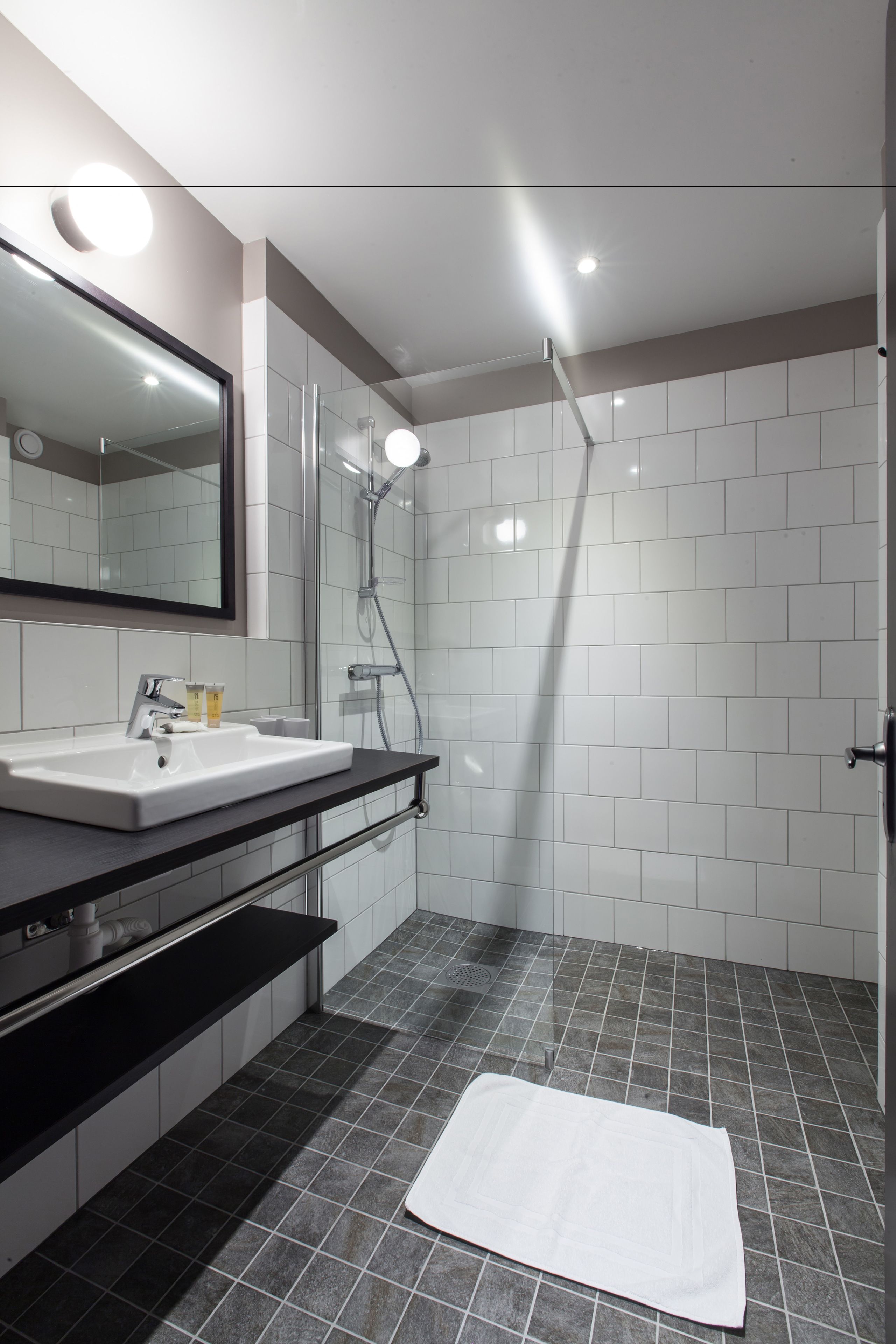 Une salle de bain moderne avec un lavabo blanc, un miroir et une douche.