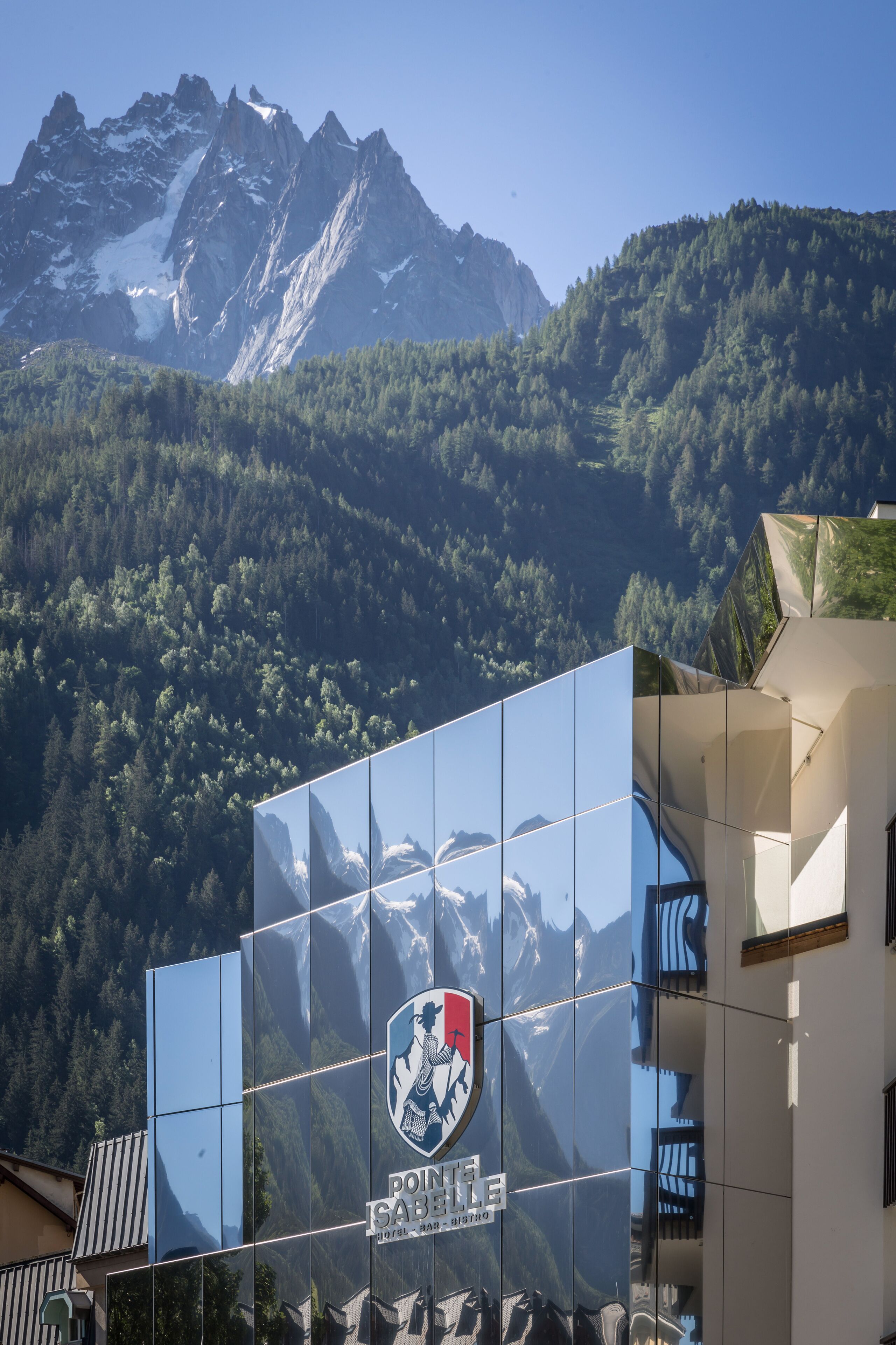 A building with a large reflective glass facade displaying a mountain range.