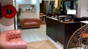 Una sala de estar moderna con un sofá, una butaca, una alfombra y una zona de cocina con mostrador y electrodomésticos.