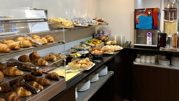 Un bufé con distintos alimentos, entre ellos pasteles, frutas y bebidas.
