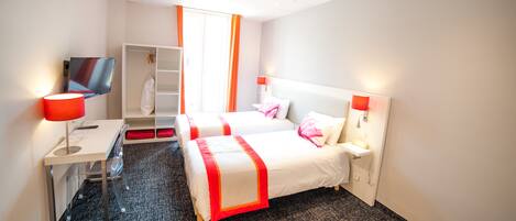 A hotel room with two beds, a desk, a TV, and a wardrobe.