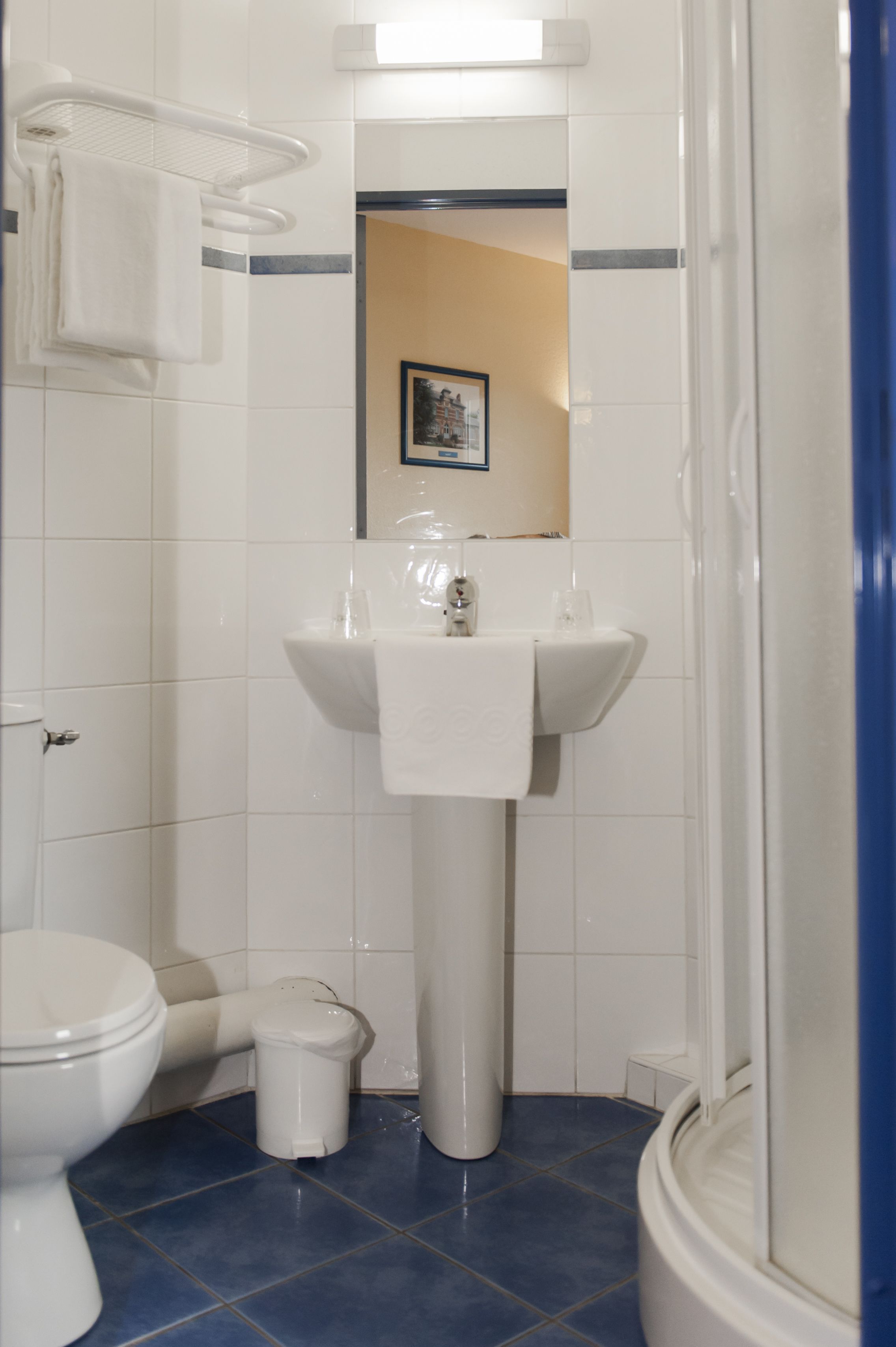 Un baño con un lavamanos blanco, un inodoro y un pequeño cubo de basura.