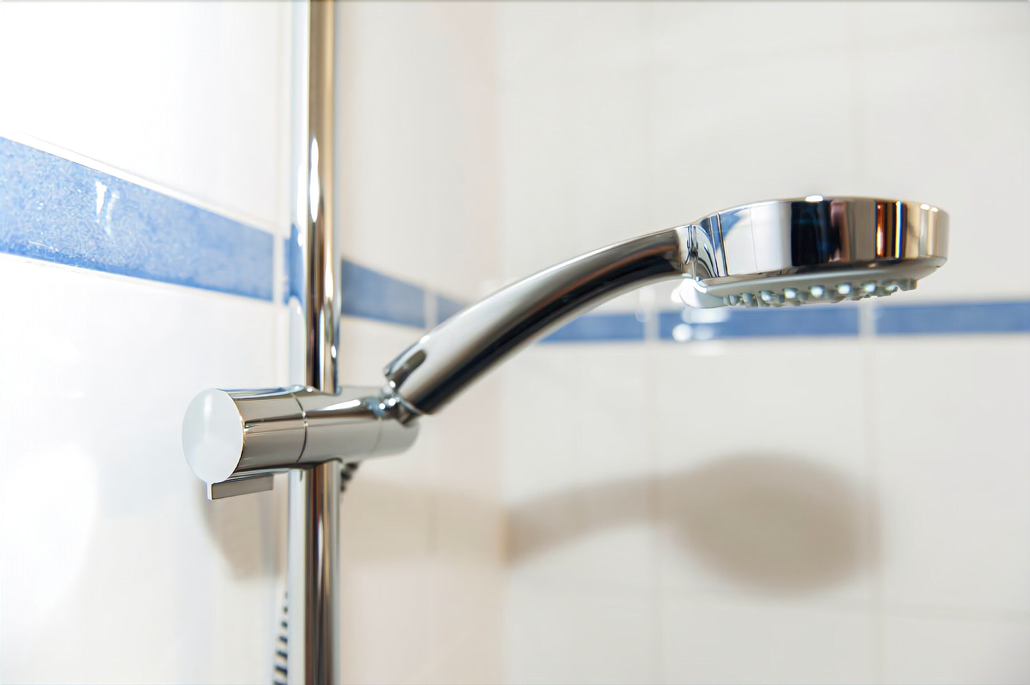 Ein chromfarbener Duschkopf an einem an der Wand befestigten Wasserhahn.
