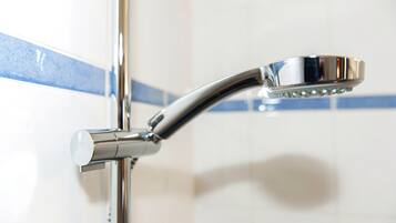 Ein chromfarbener Duschkopf an einem an der Wand befestigten Wasserhahn.