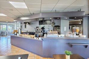 A modern cafe with a counter, menu board, and various coffee-making equipment.