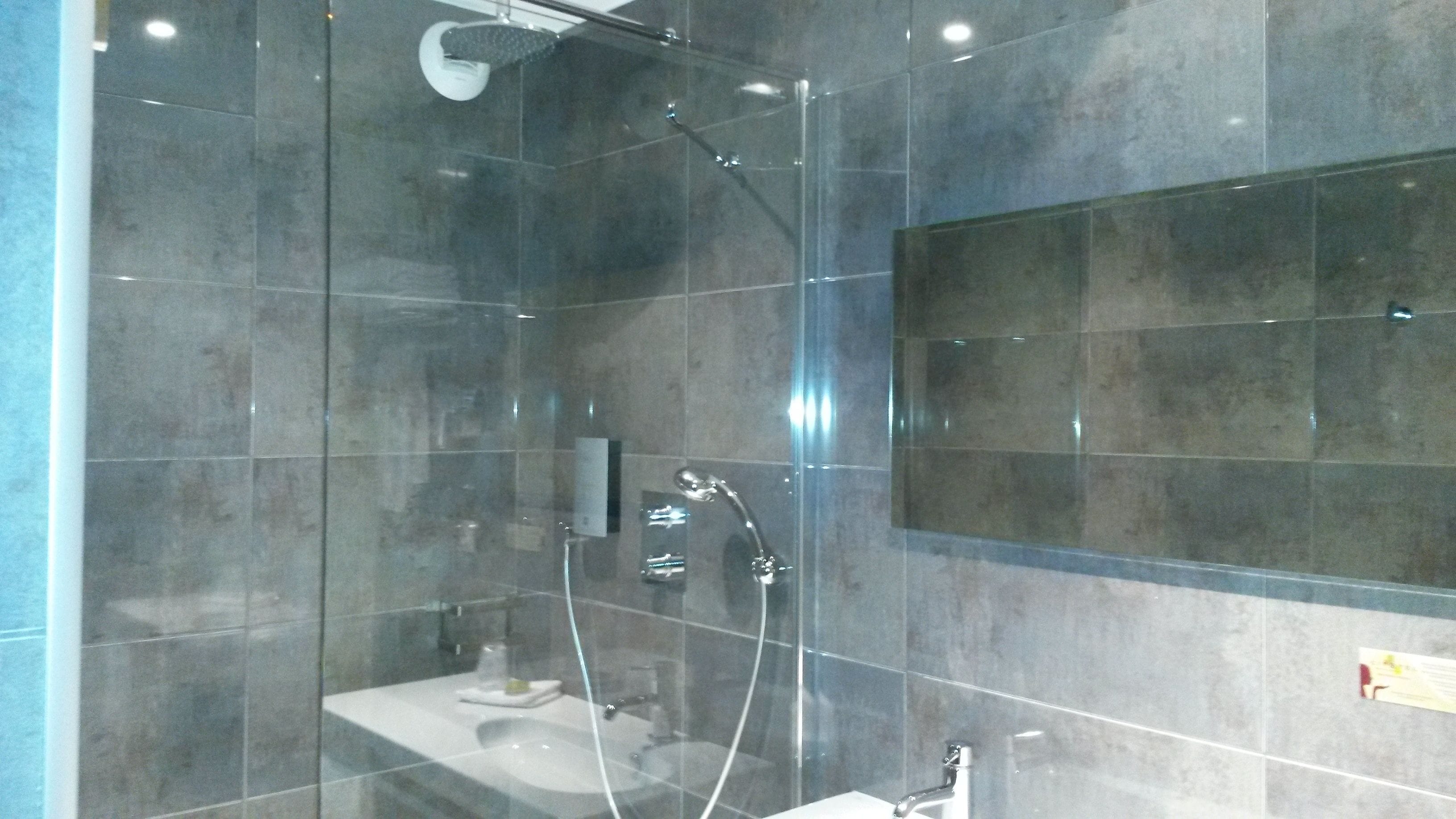 Een moderne badkamer met een douchecabine van glas, een wastafel en een spiegel.