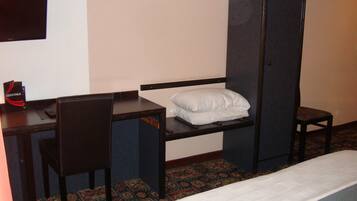 A hotel room with a single bed, a desk with a chair, a wardrobe, and a small table with a menu.