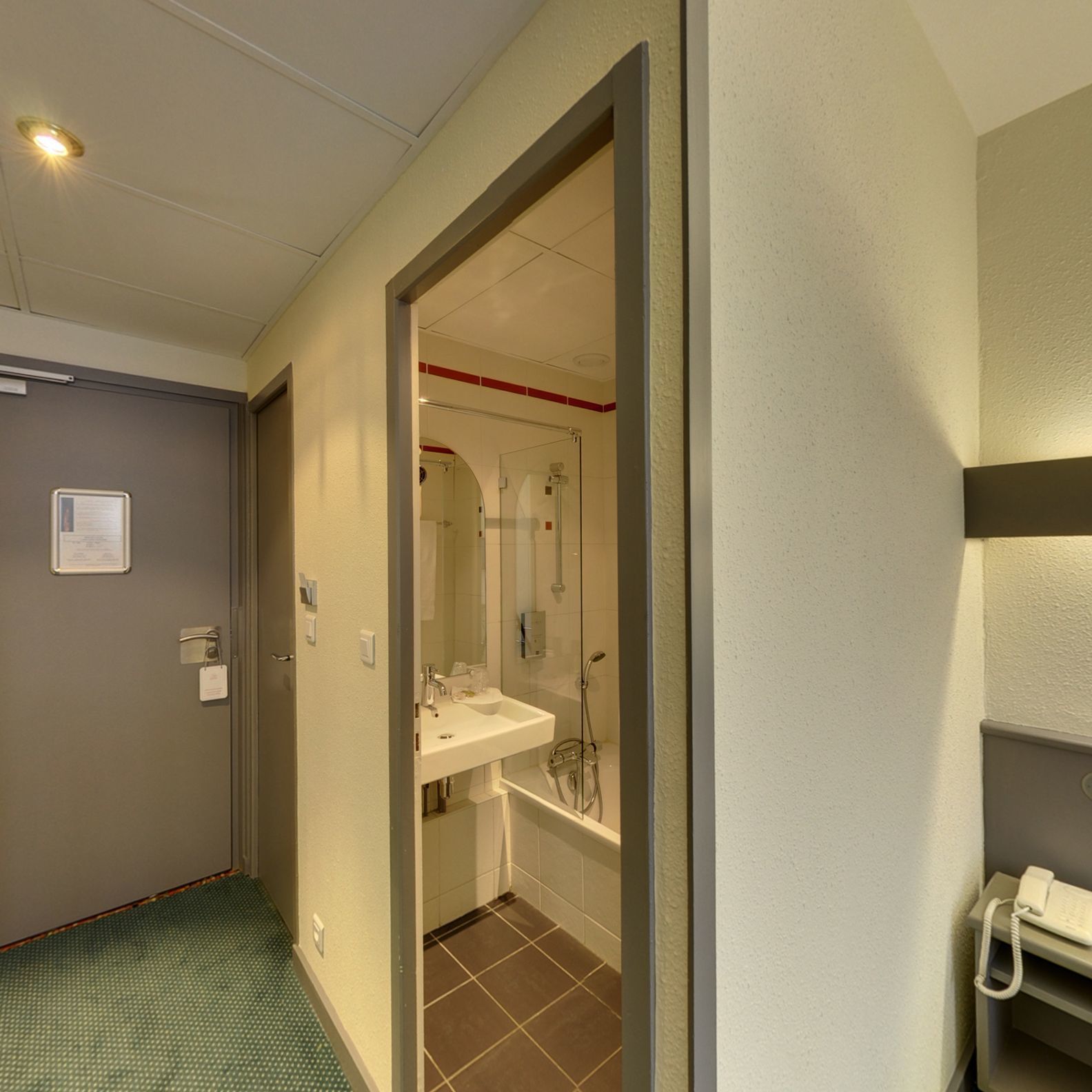Un baño de hotel con ducha, lavamanos e inodoro.