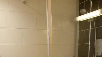 A shower with a glass door, a white towel on the floor, and a towel hanging on a rack.