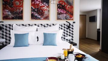 A hotel room with a large bed, geometric-patterned headboard, and abstract artwork on the walls.